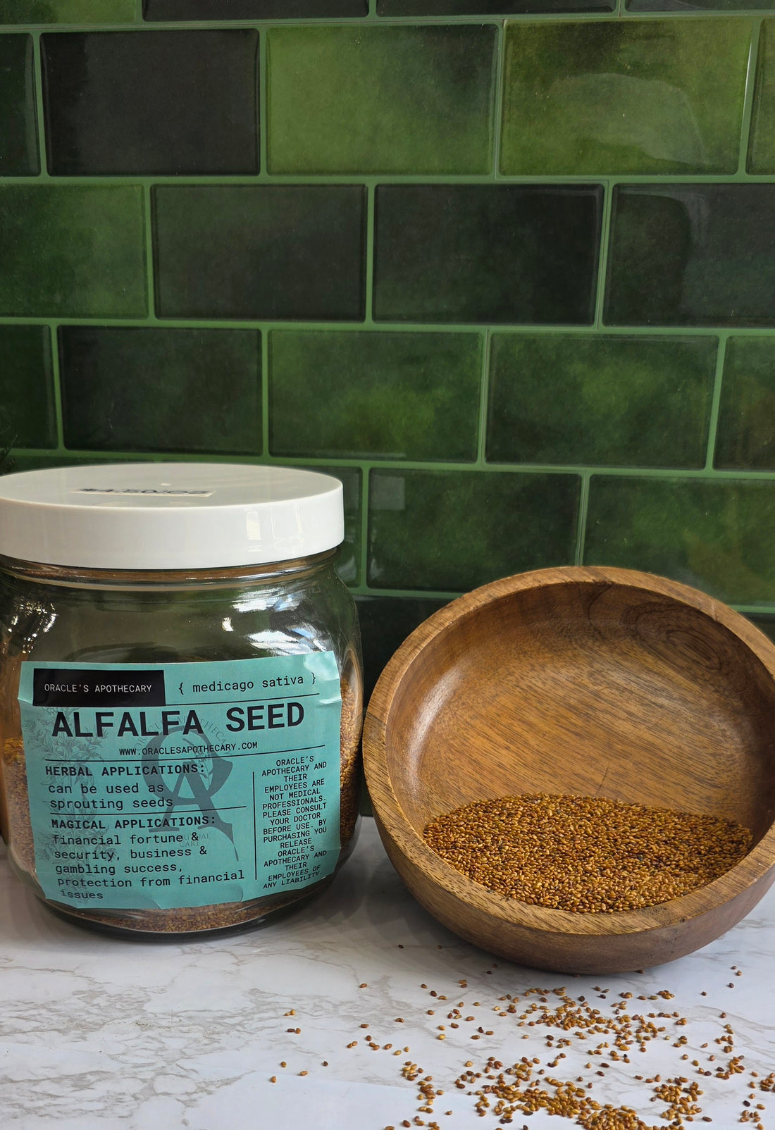 Alfalfa Seed in clear jar with label and in wood bowl on a marble counter top with green tile background