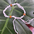 a white threaded bracelet with 3 wooden beads braided into it.
