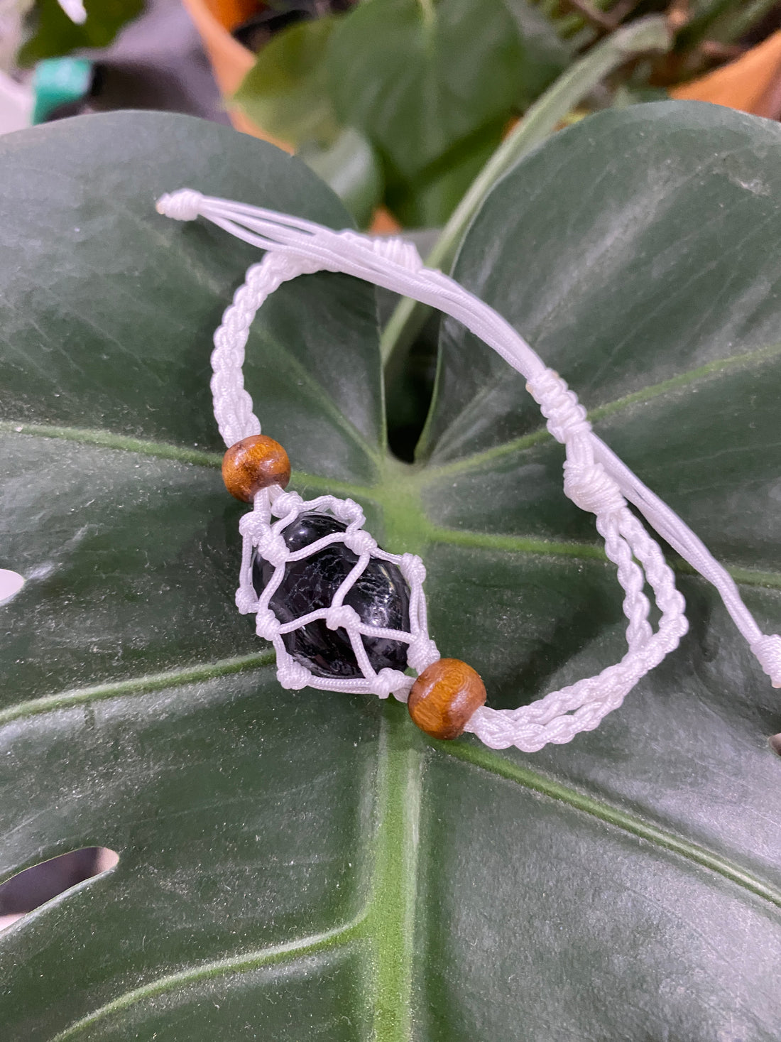 a white threaded bracelet with a black stone braided into it.