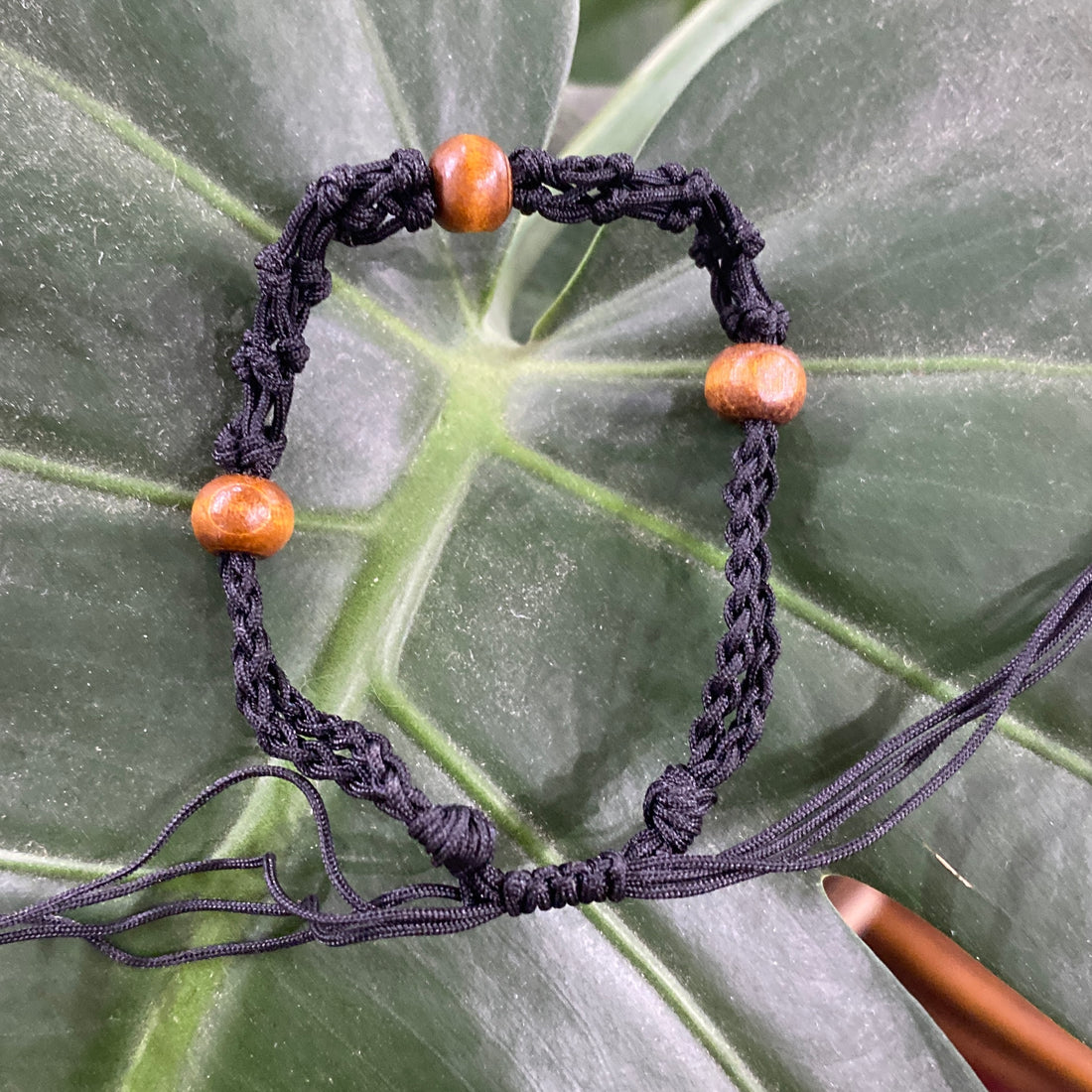 a black threaded bracelet with 3 wooden beads braided into it.