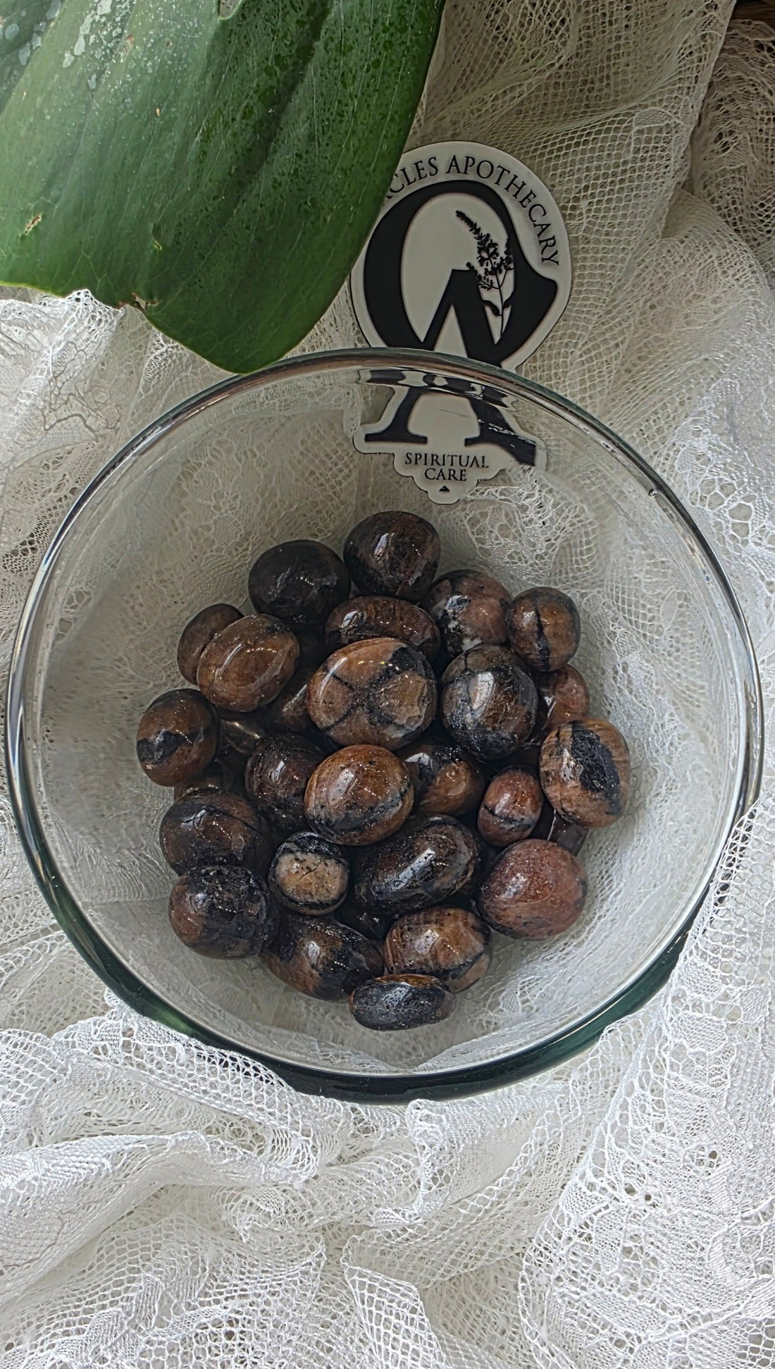 Glass bowl with dark berries on a white lace tablecloth with a brand label in the background.