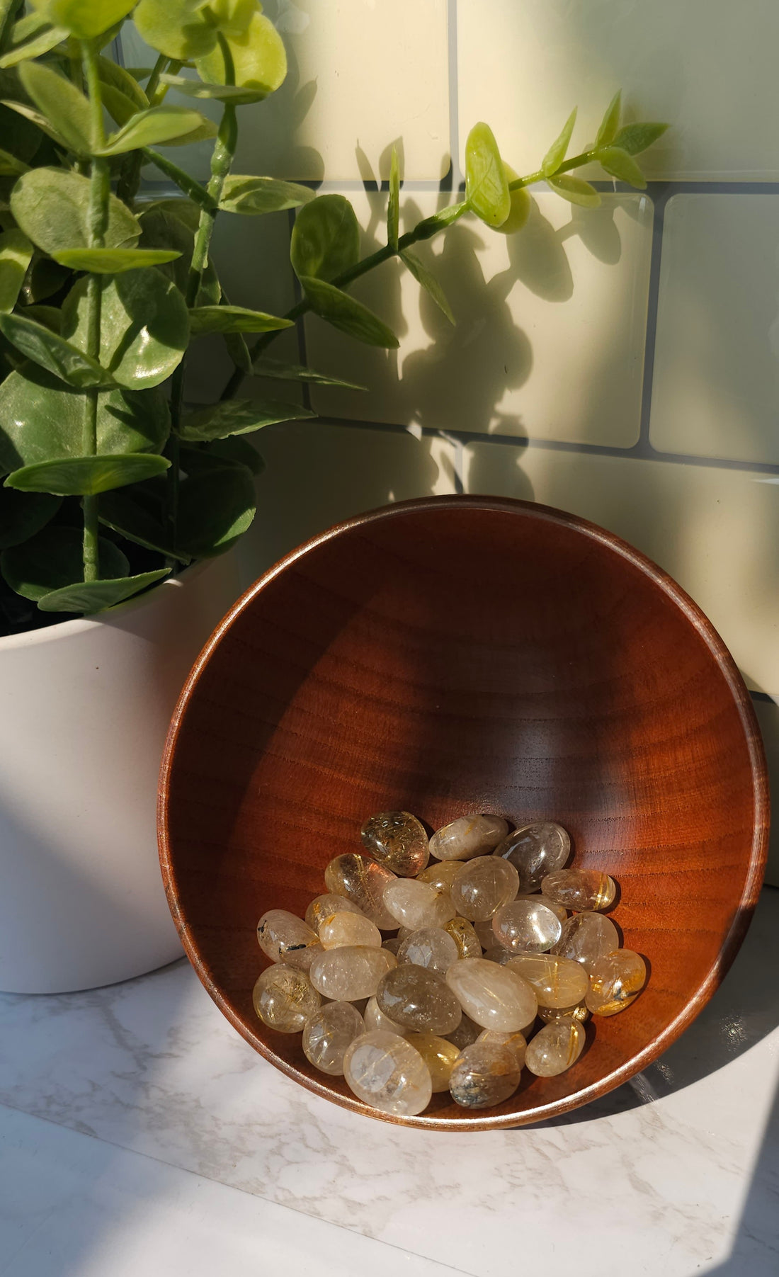 Golden Rutile crystals stones in a wooden bowl