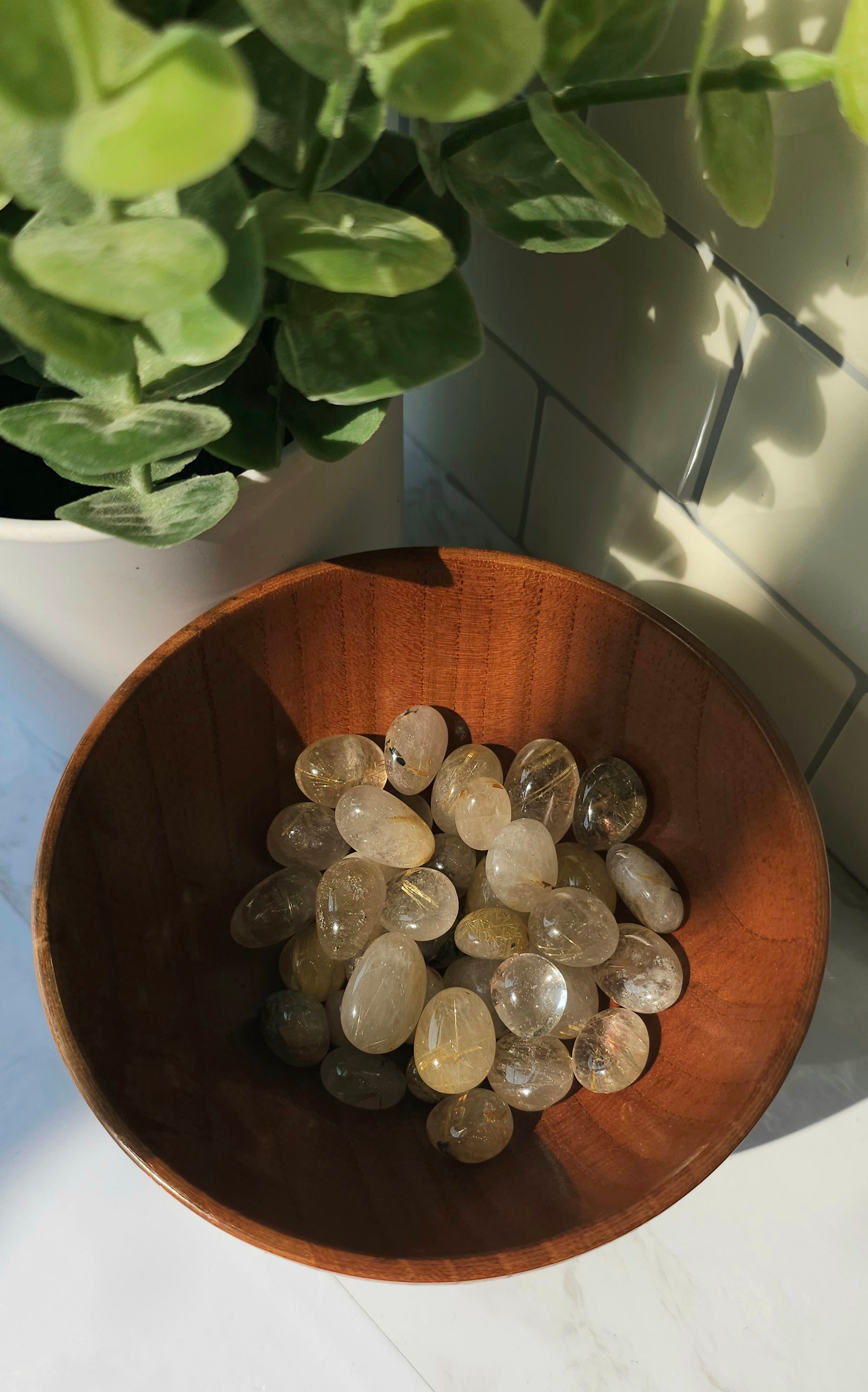 Golden Rutile crystals stones in a wooden bowl