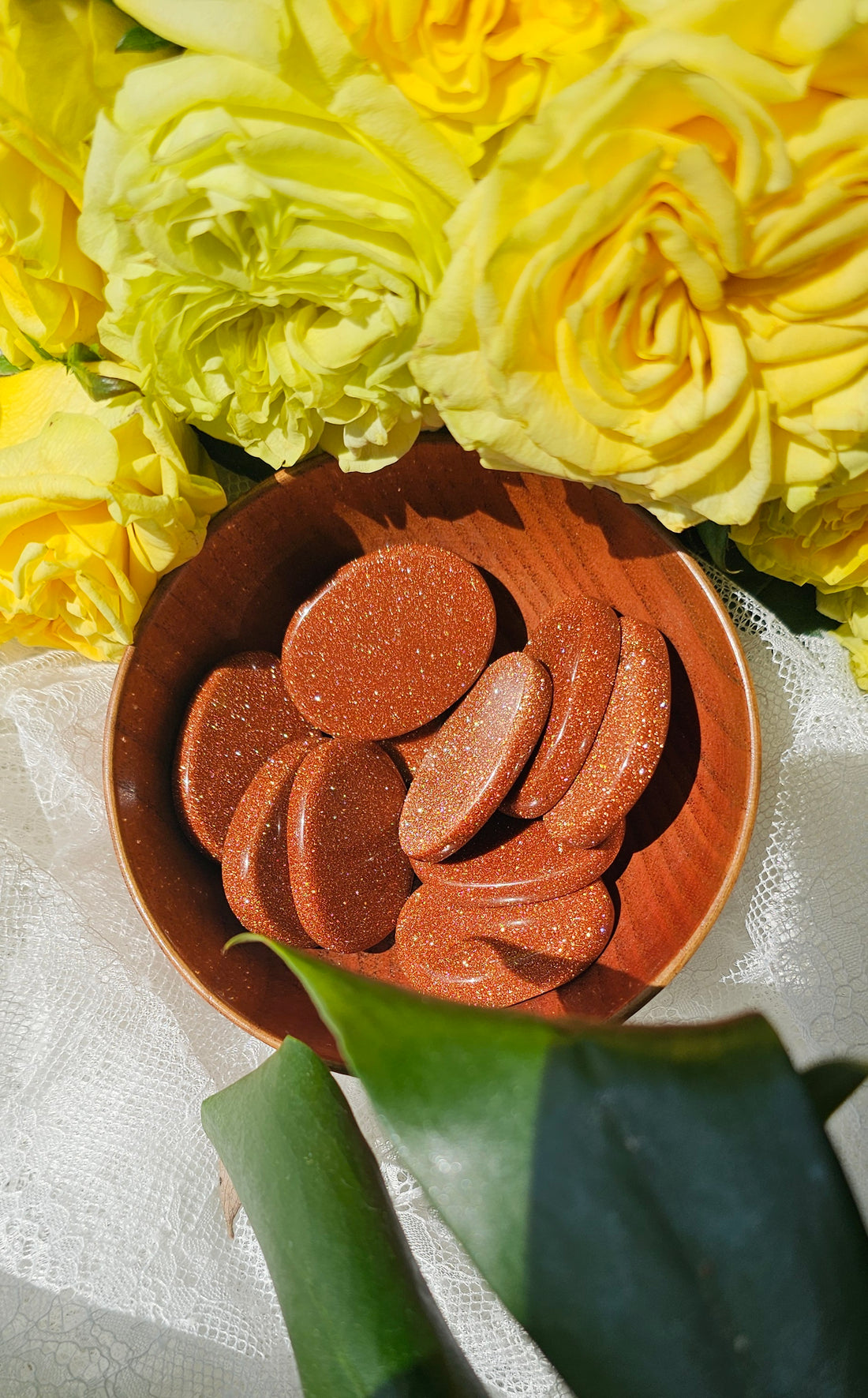 Happy Stones in a wooden bowl surrounded by flowers