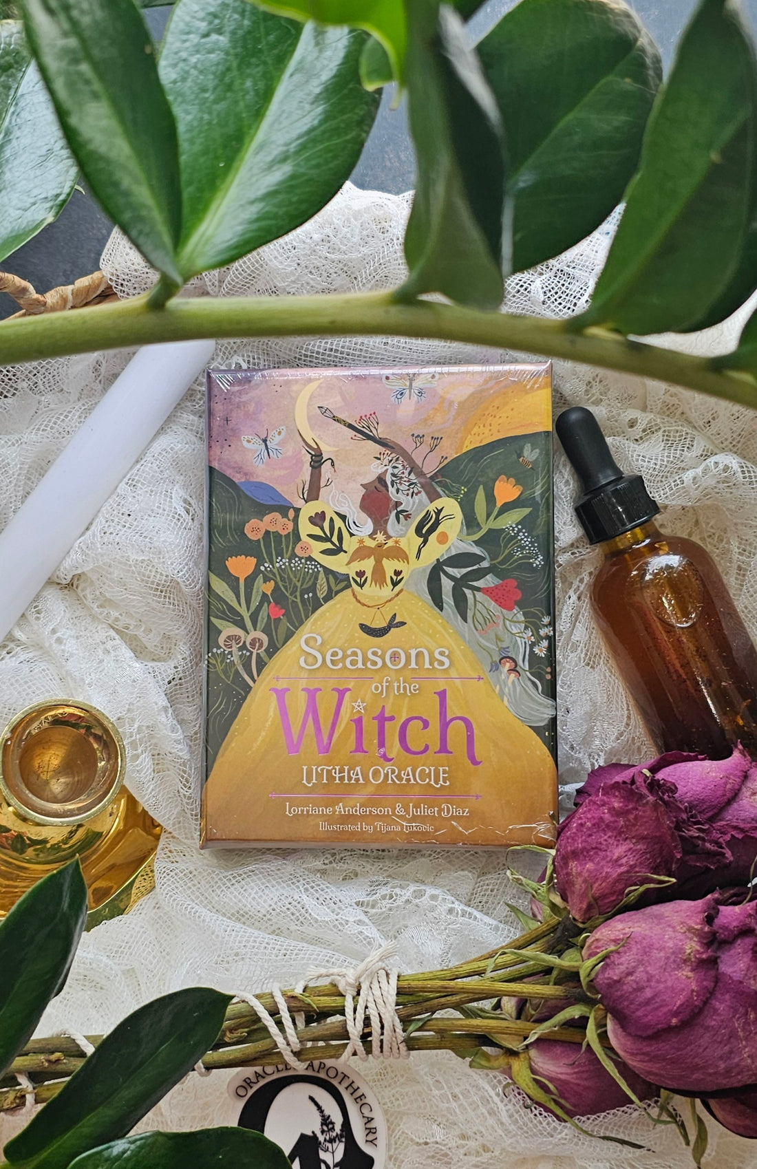 Seasons of the Witch: Litha Oracle deck lying next to roses and a tincture