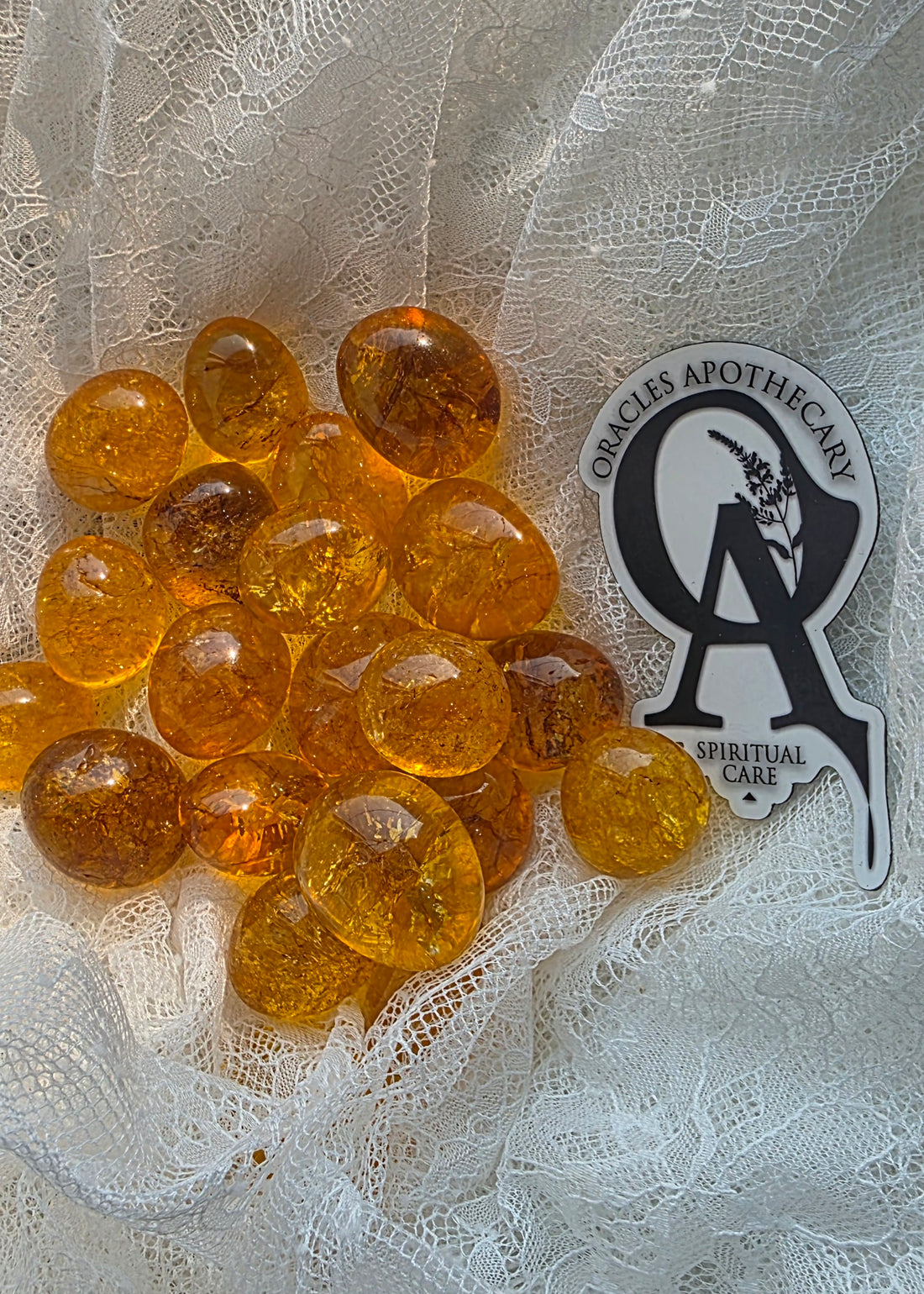 Amber-colored stones on a textured white surface with a branded label in the corner.