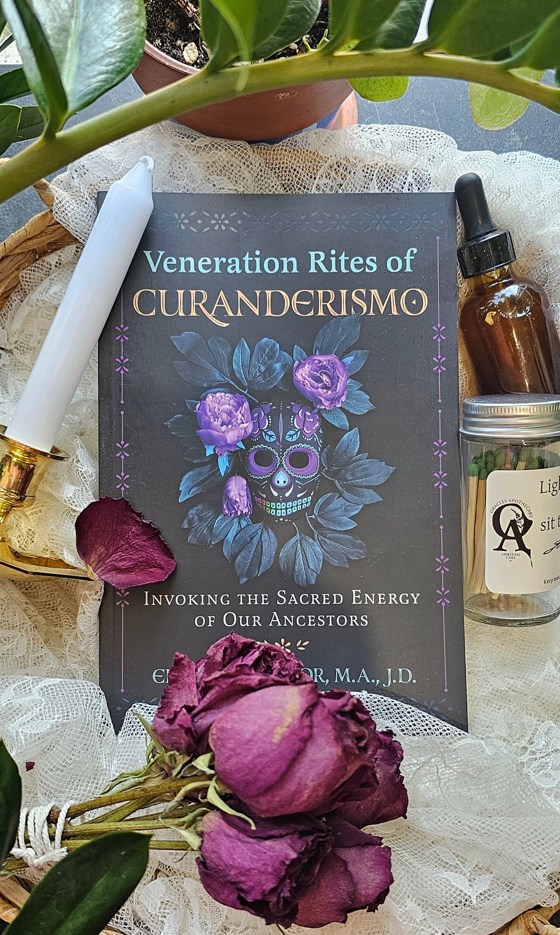 Veneration Rites of Curanderismo book lying next to roses and a tincture