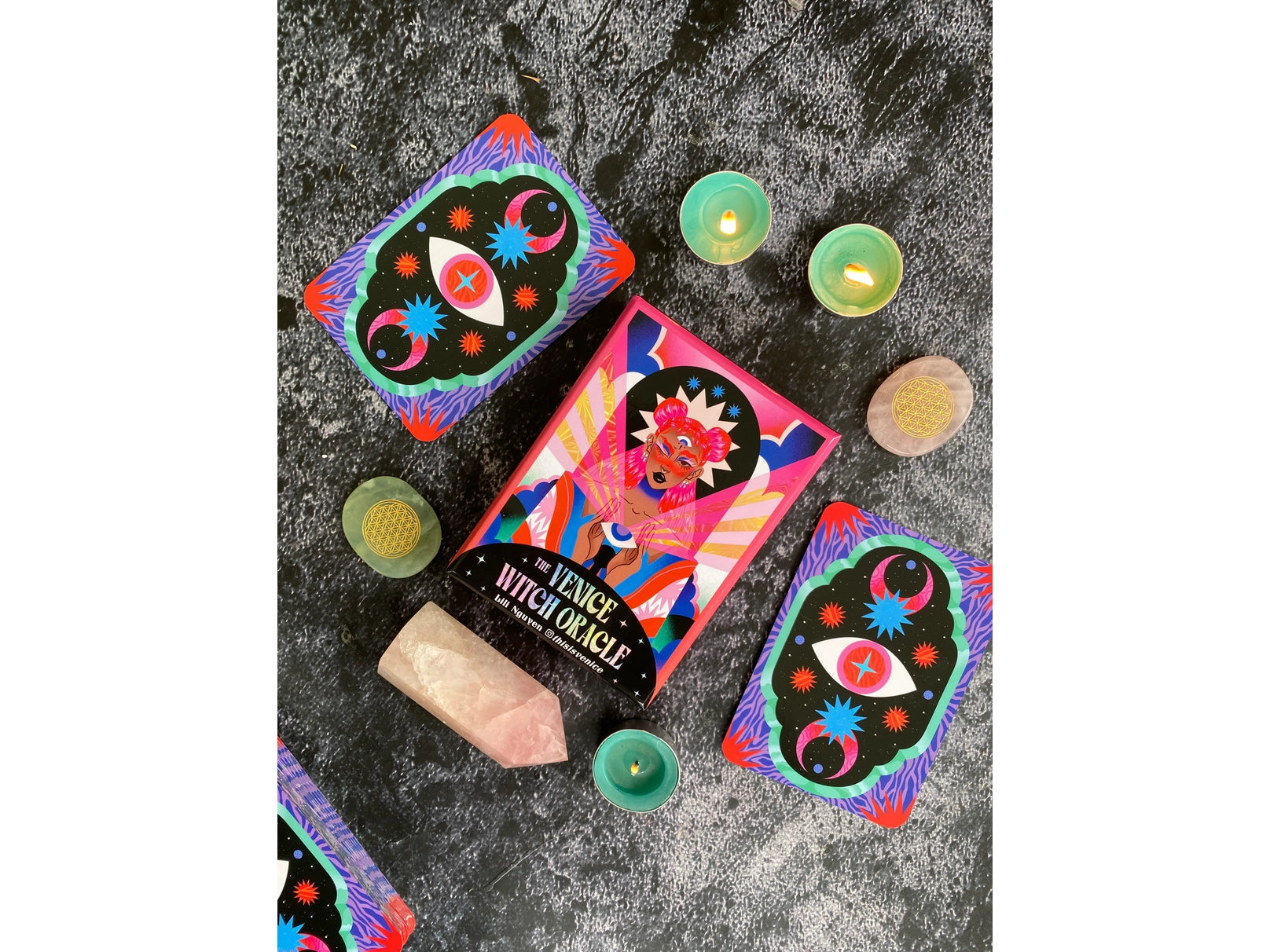 Colorful witchy-themed products on a dark surface with candles