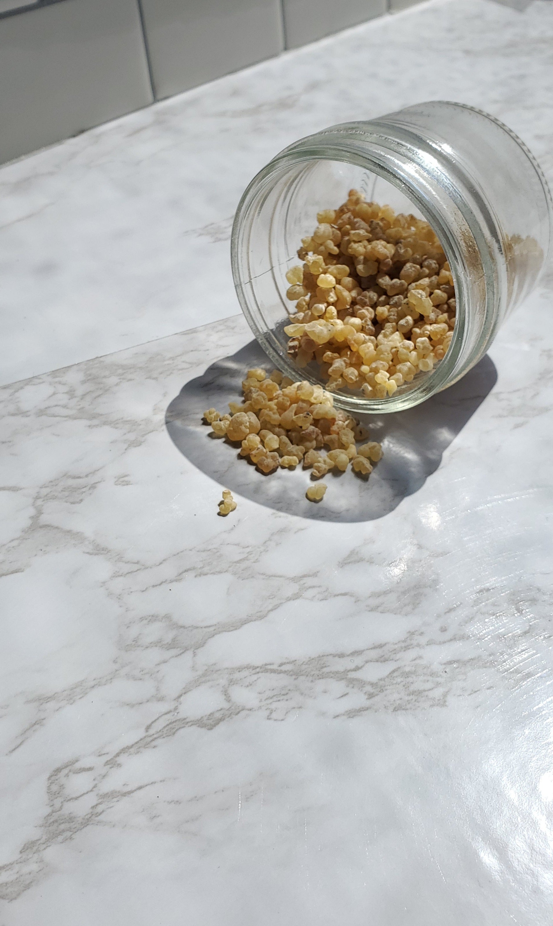 Frankincense Tears spilling from a glass jar on to a white table