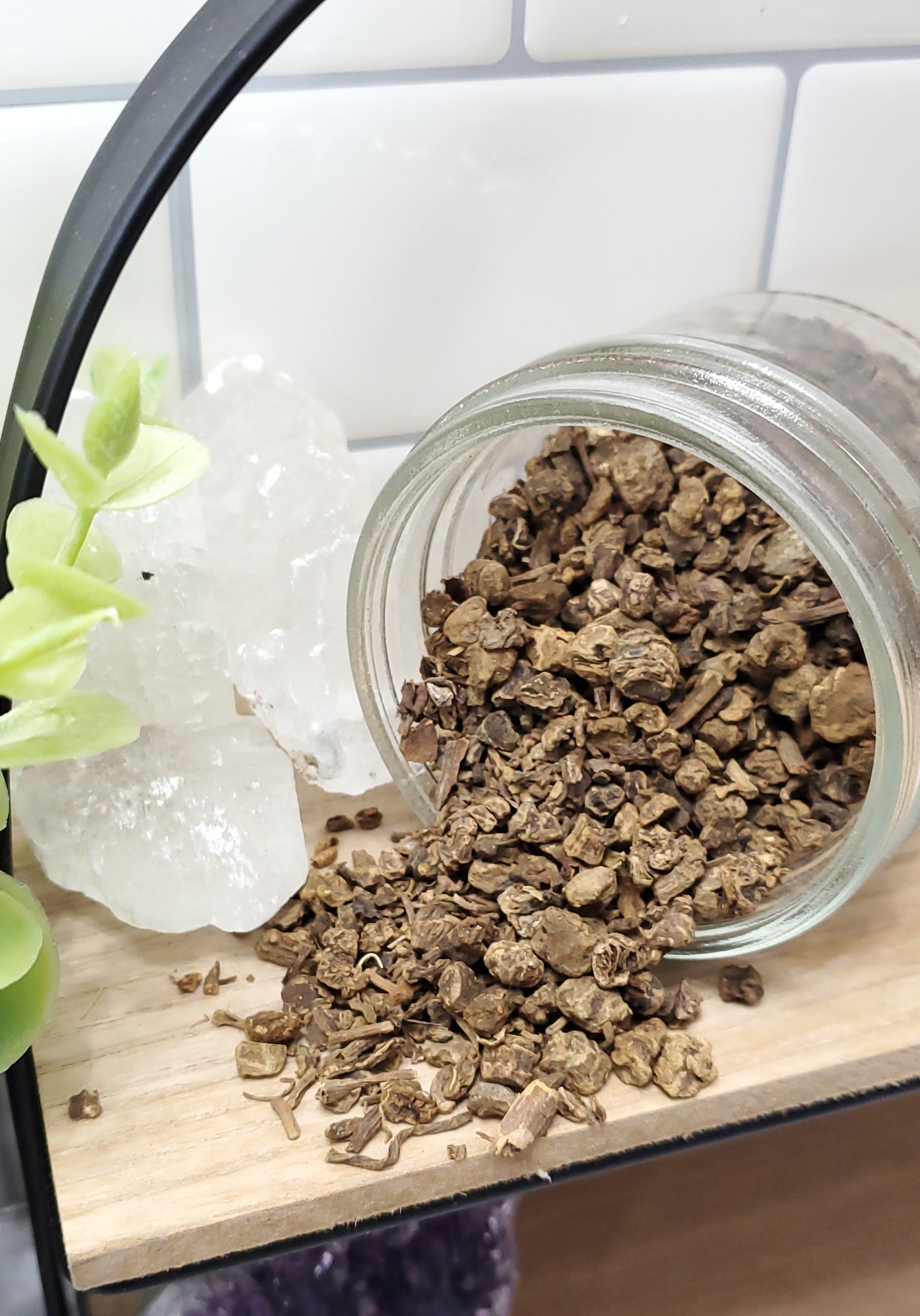 valerian root spilling out of glass jar on to wooden shelf