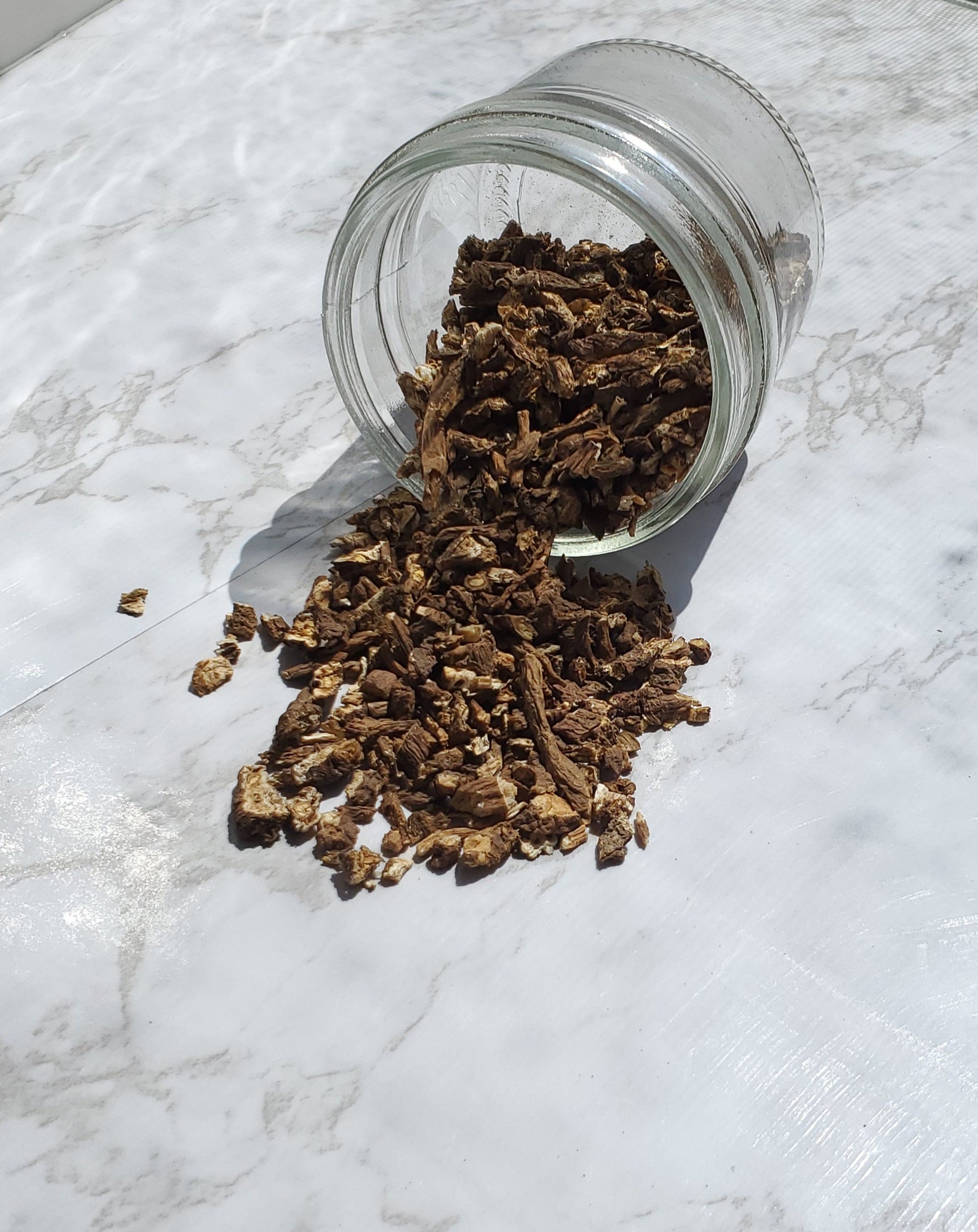 dandelion root spilling out of a glass jar on to a table