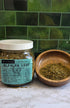 Alfalfa leaf in a jar with a label and loose on a wooden bowl with a green background 