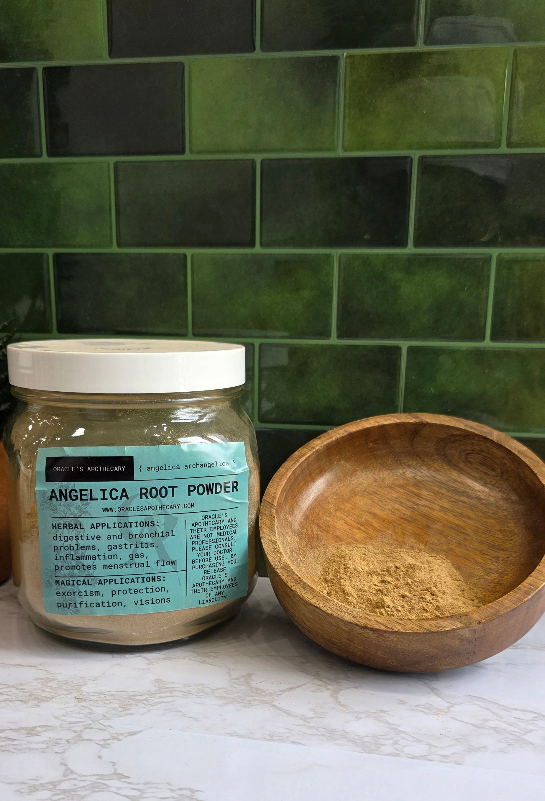 Jar of angelica root powder with a teal label and a wood bowl with powder and a green background and white counter 