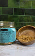  Astragalus Root in clear jar with label and in wood bowl on a marble counter top with green tile background 