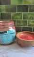 Organic Beetroot Powder in clear jar with label and in wood bowl on a marble counter top with green tile background 