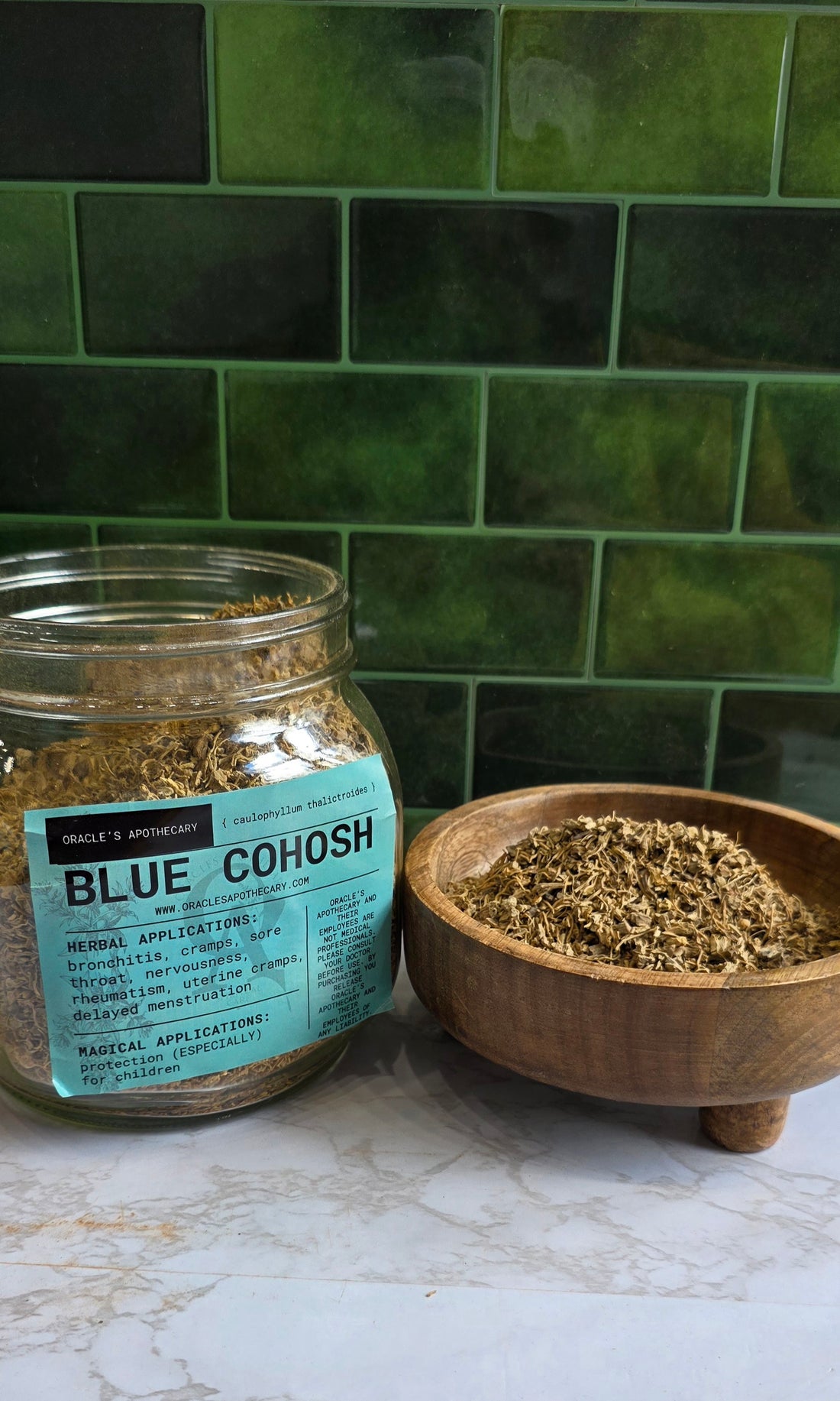 Blur Cohosh in clear jar with label and in wood bowl on a marble counter top with green tile background
