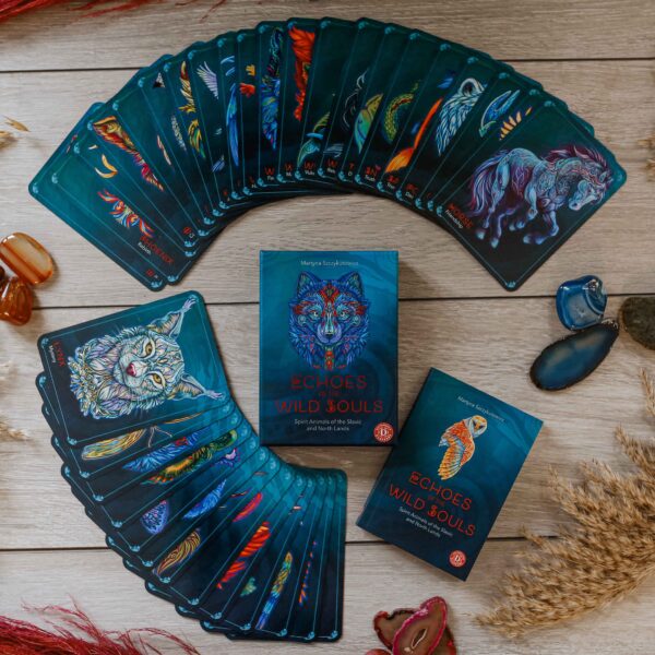 spread of all the cards of the deck, guidebook, and card box on a wood table