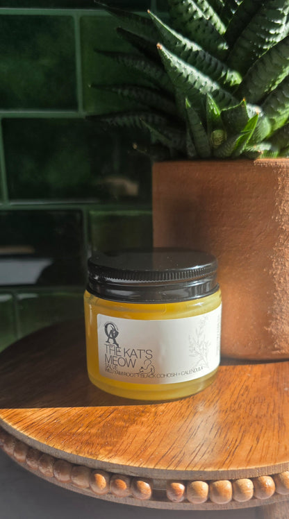 Jar of cream on a wooden surface with a plant in the background