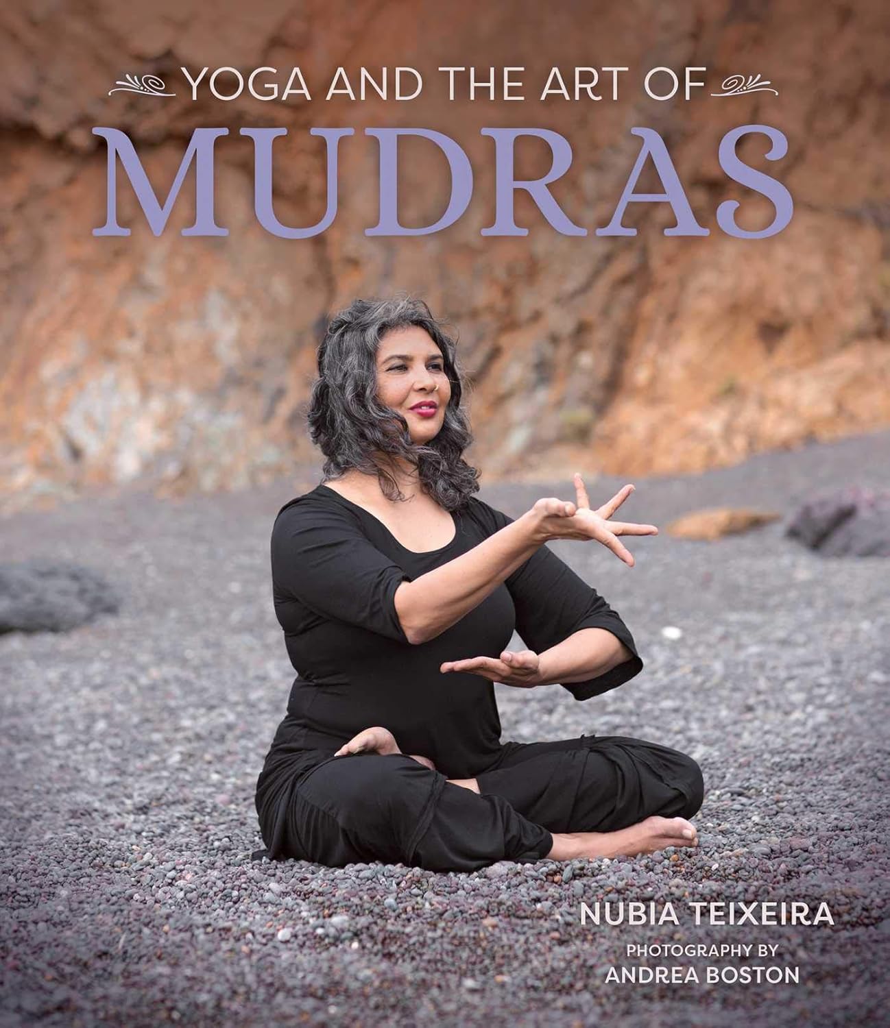 Woman practicing yoga on a rocky beach with &