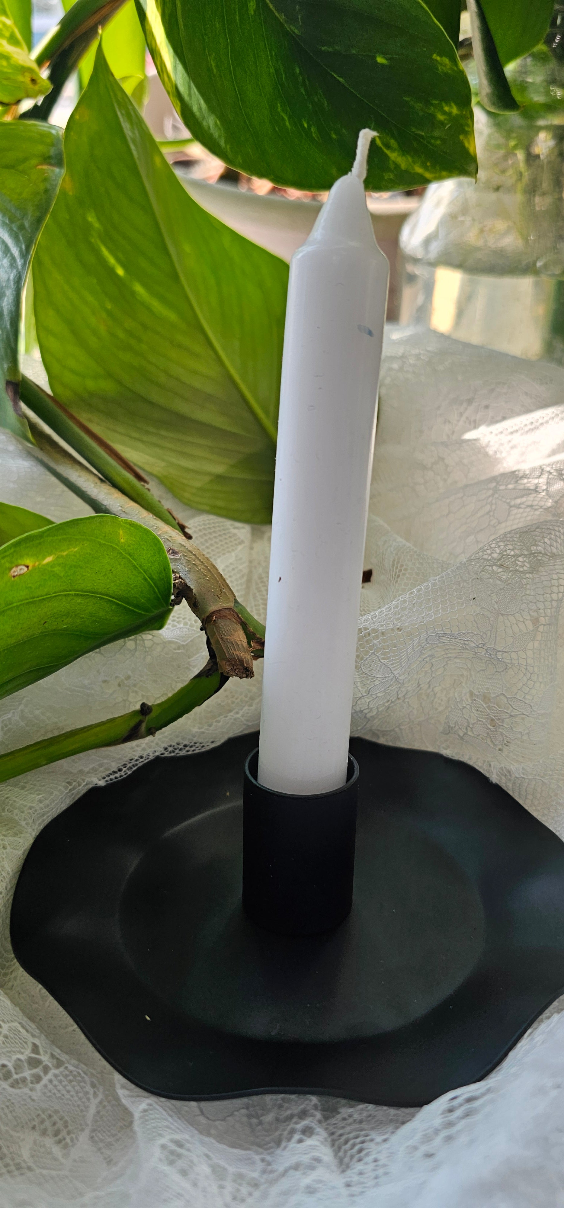 a white candle in a black candlestick holder with waved edges