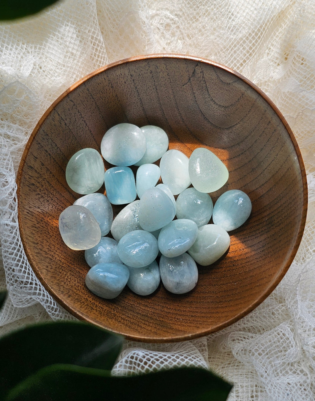 a wooden bowl filled with Aquamarine crystals stones