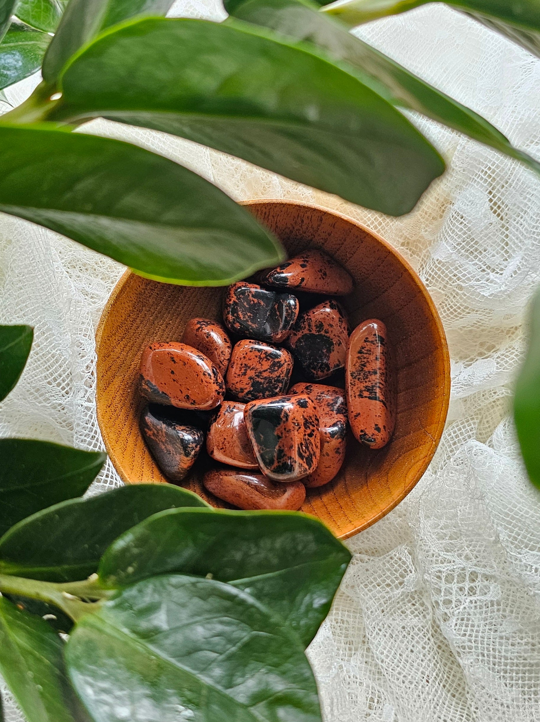 Mahogany obsidian crystals stones piled in a wooden bowl