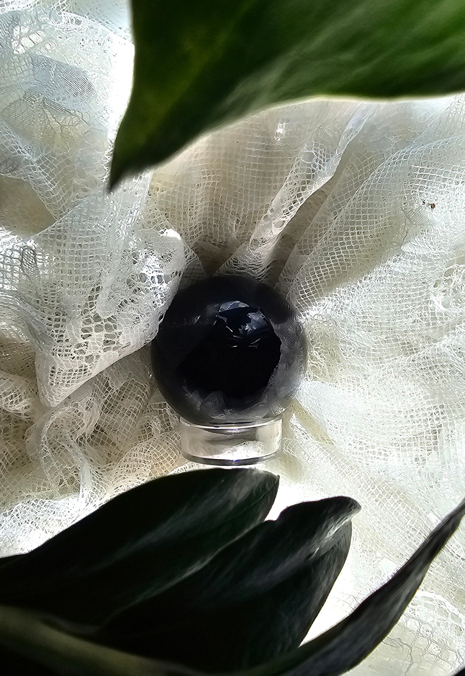 obsidian sphere crystals stones displayed with white lace around it