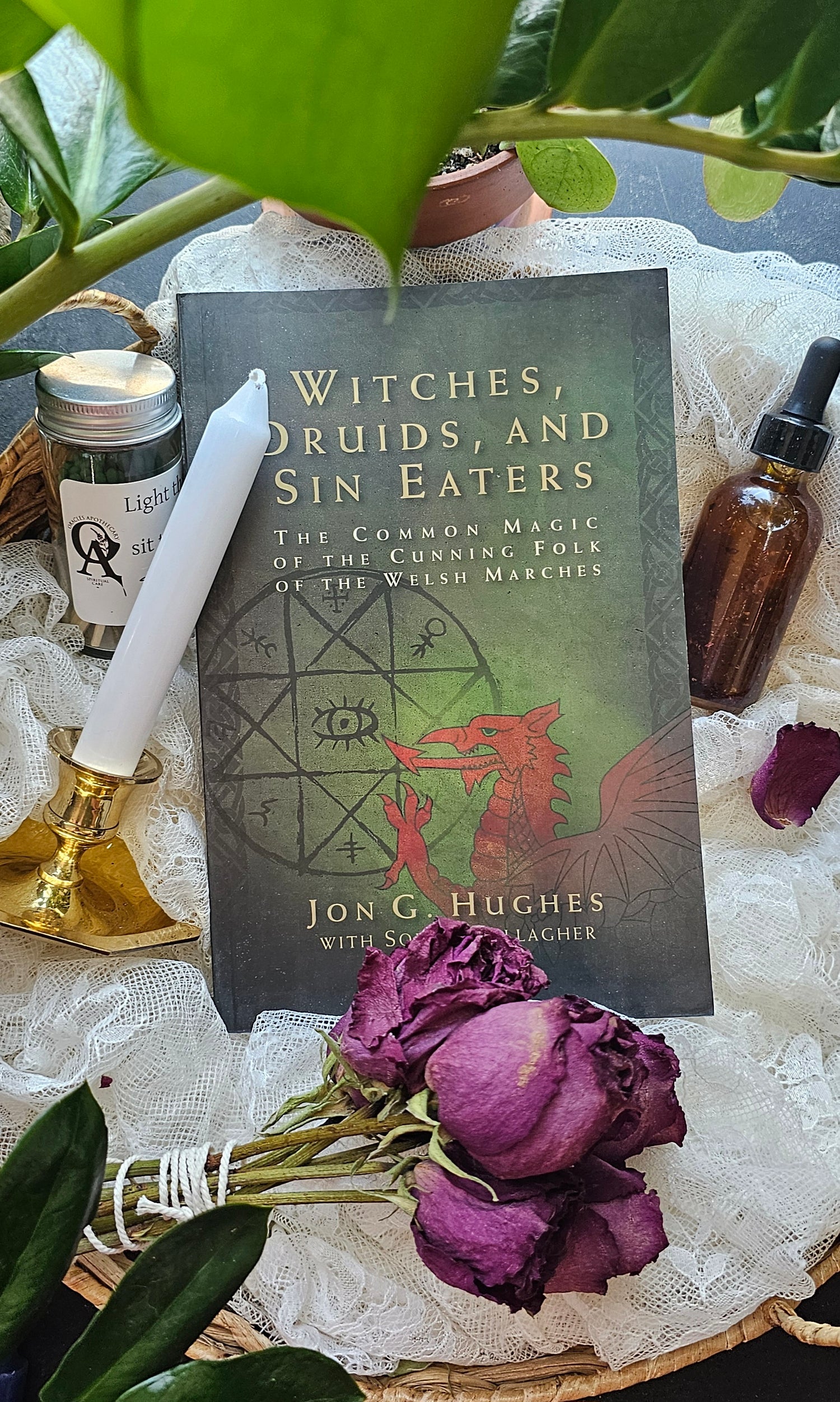 Witches, Druids, and Sin Eaters book lying next to tincture and roses