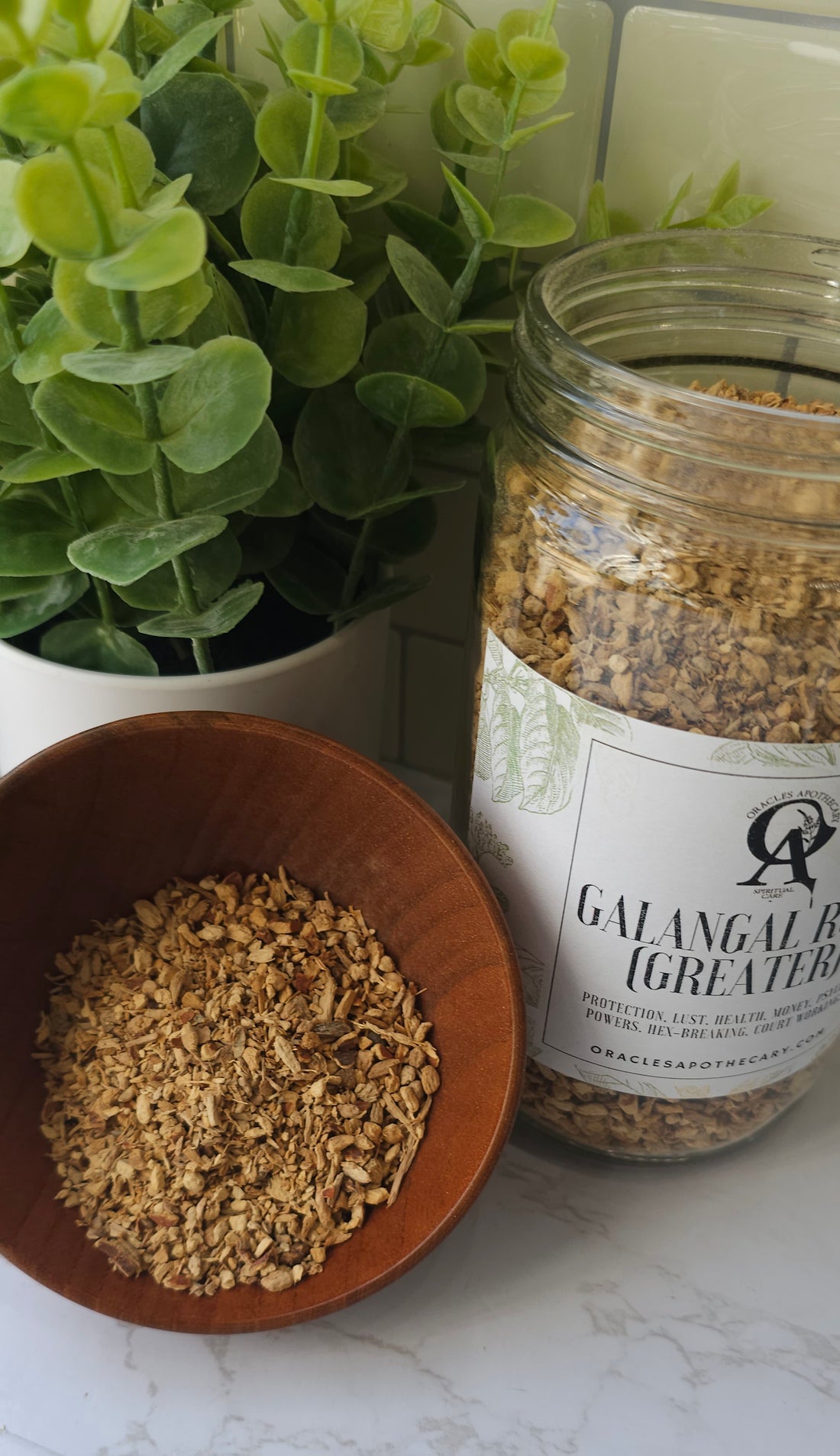 Greater Galangal Root in a wooden bowl next to a glass jar of the herb