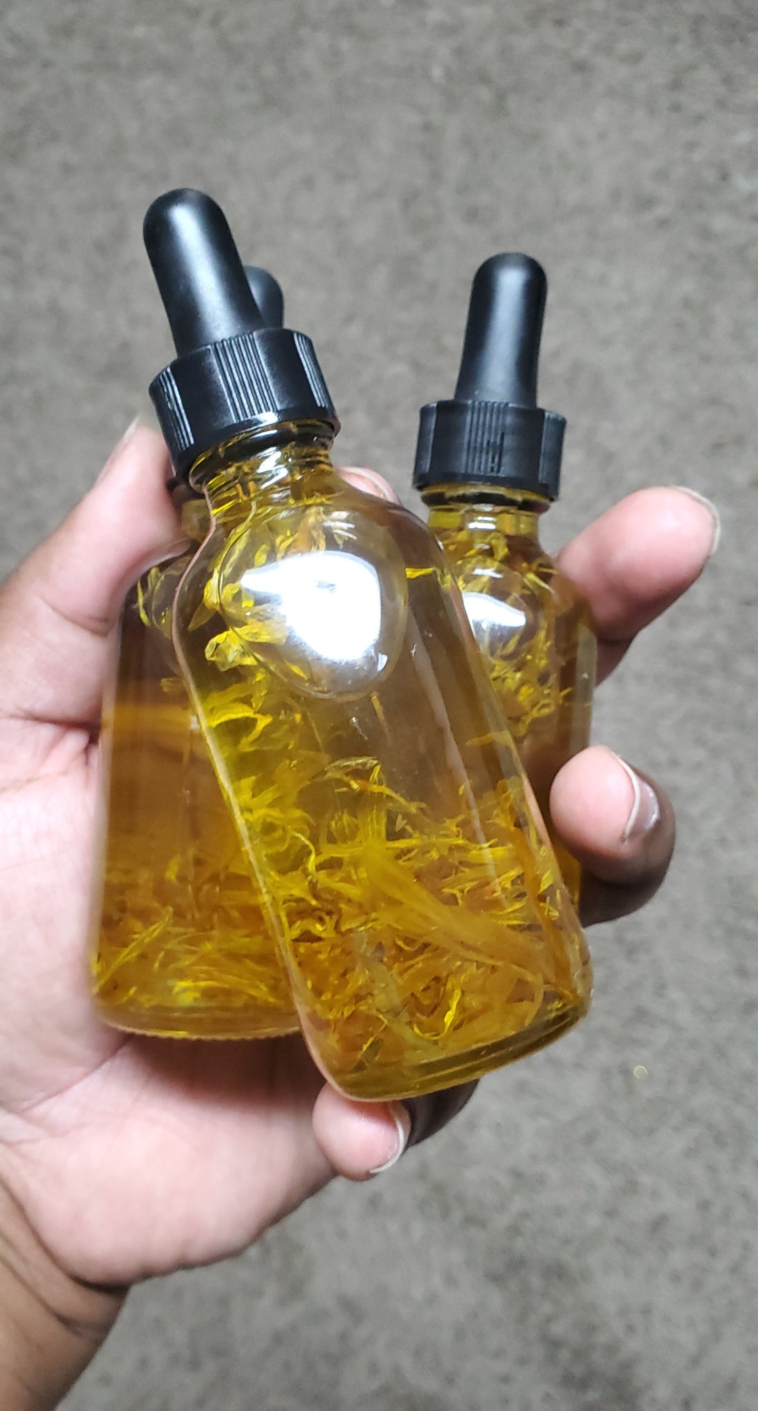hand holding dropper bottle filled with oil and calendula