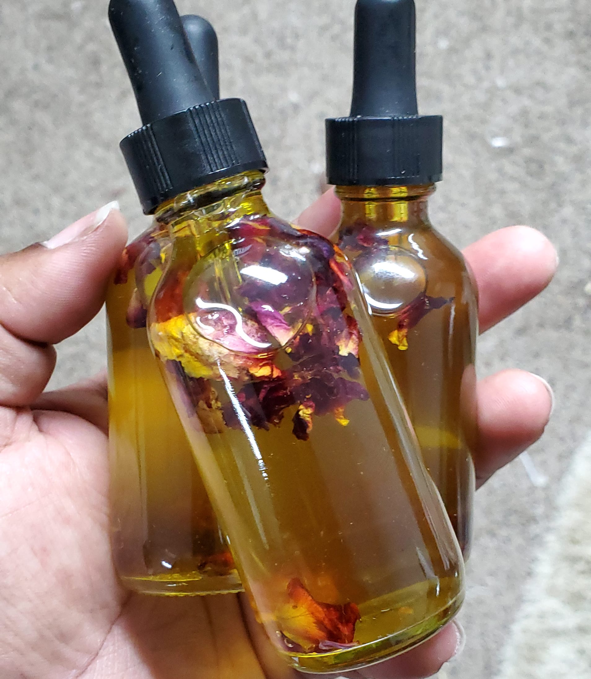 hand holding oil dropper with roses inside