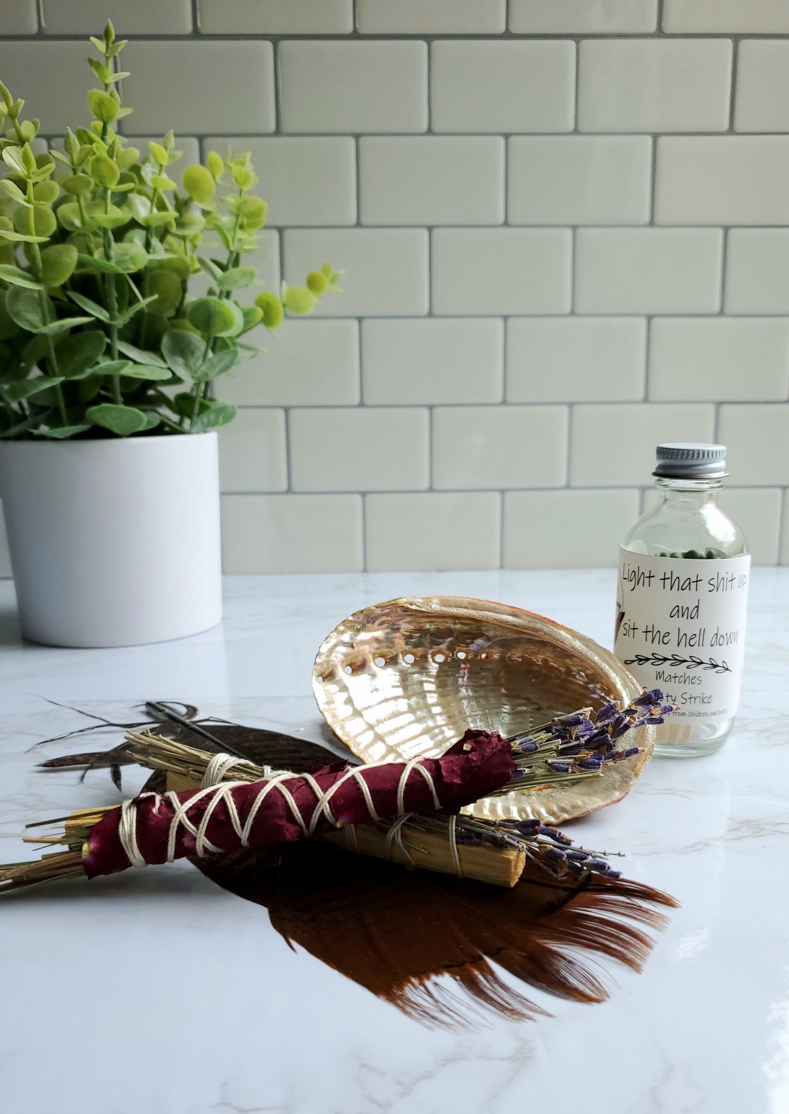 an Abalone Shell with a turkey feather and sage stick beside it