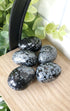 Snowflake Obsidian crystals stones piled up on wooden shelf