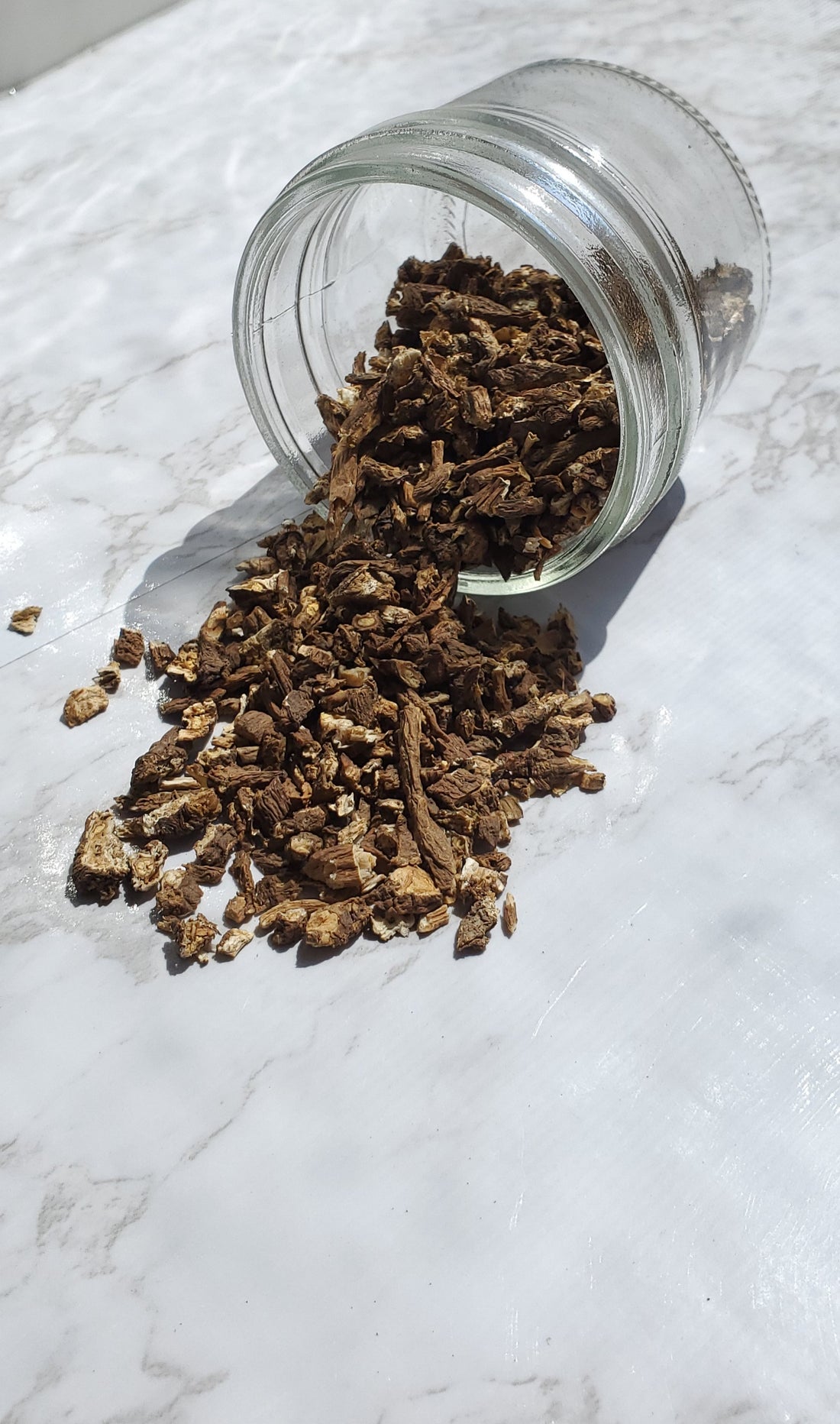 dandelion root spilling out of a glass jar